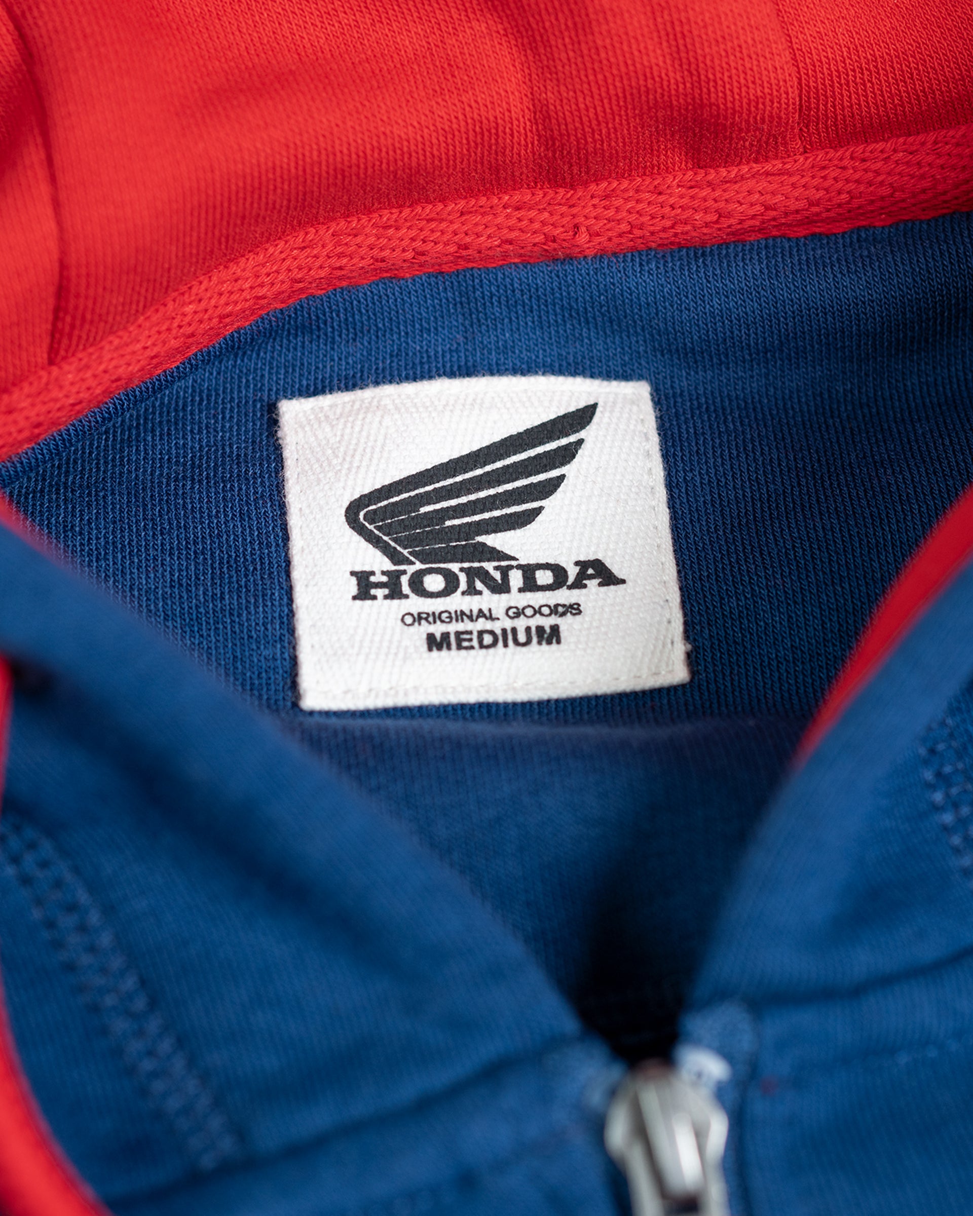 Eingenähtes Honda Original Goods Etikett in Größe Medium im Nacken des blauen Zip-Hoodies, rotes Kapuzenfutter.