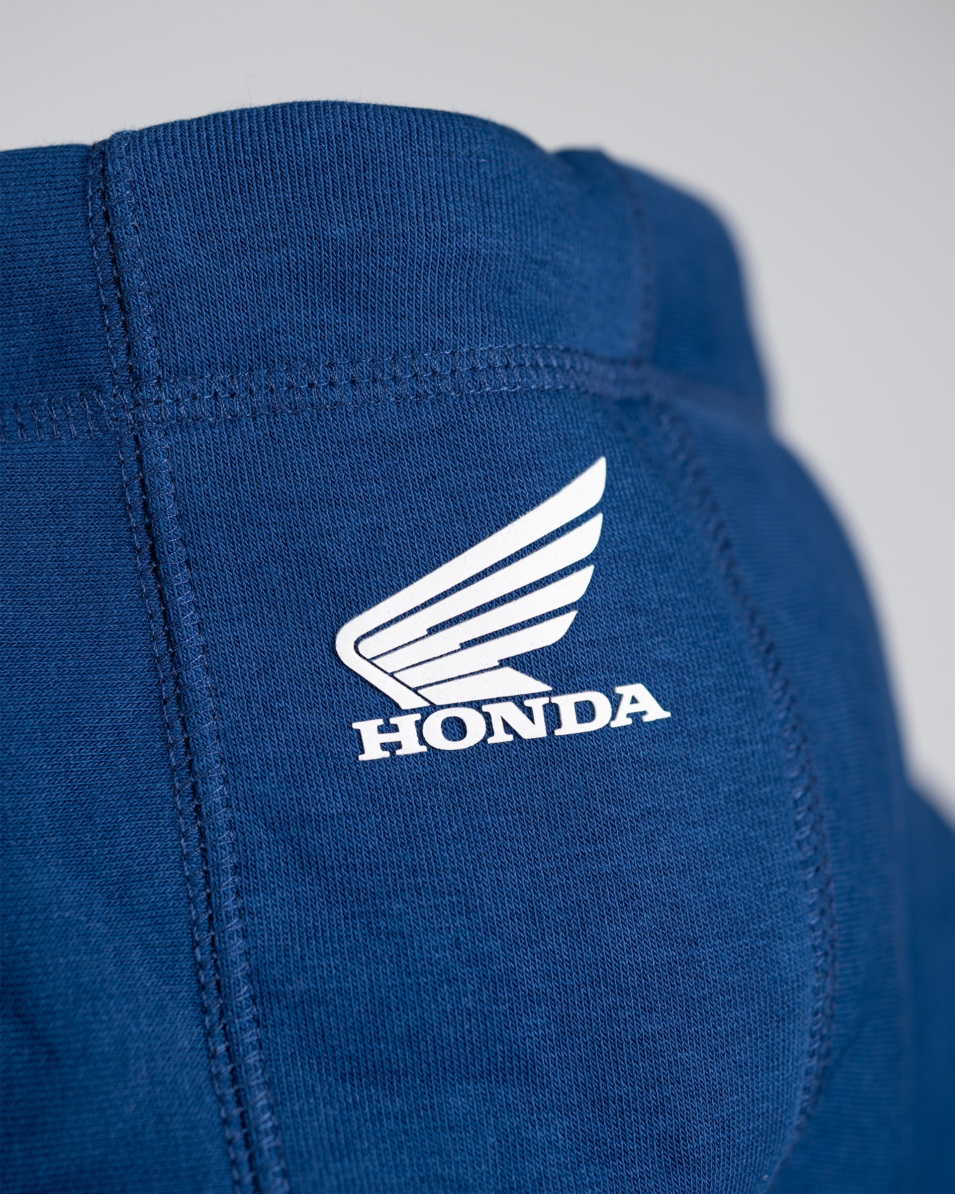 Weißes Honda Flügel-Logo auf der Kapuze des blauen Zip-Hoodies.